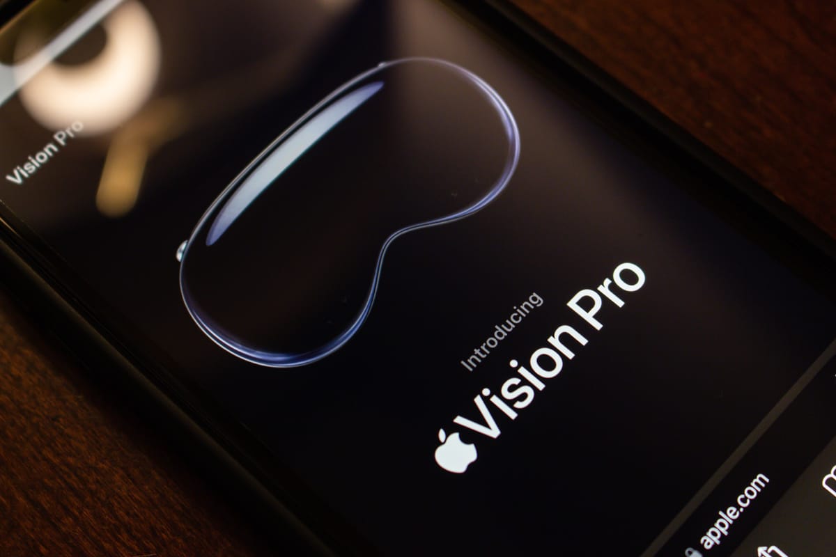 An official website of Apple Vision Pro seen in an iPhone on a wooden table.