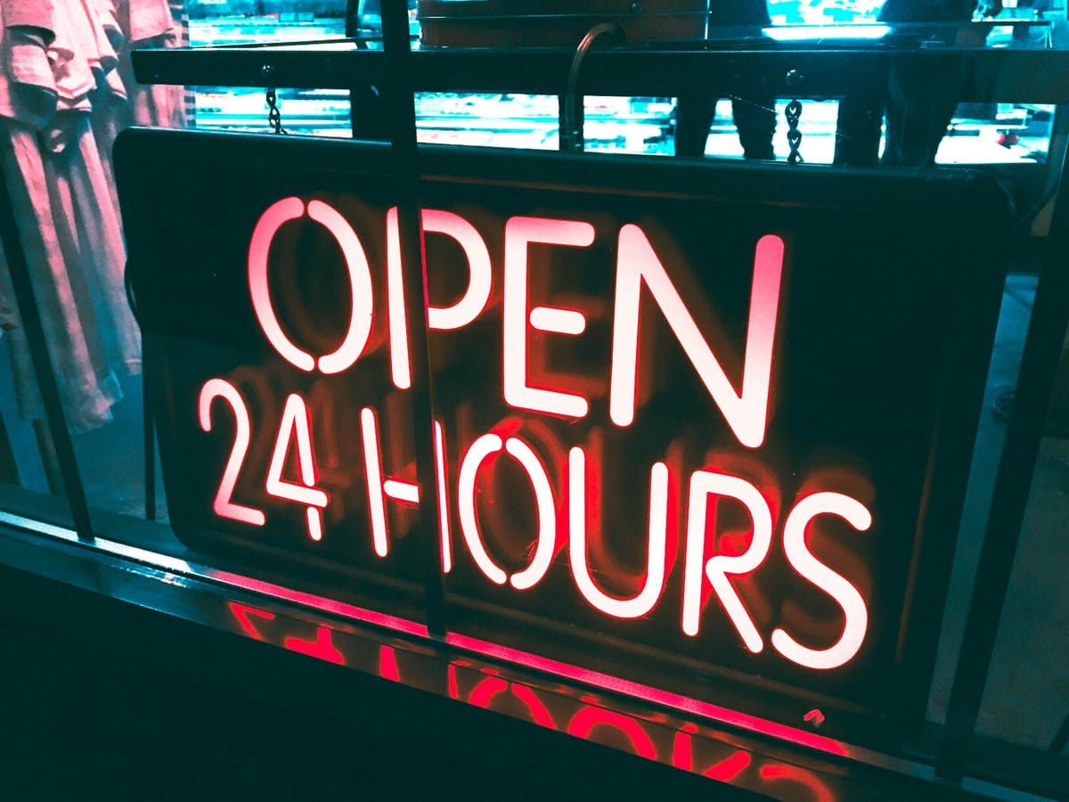 A neon "Open 24 hours" sign in the front window of a cafe.